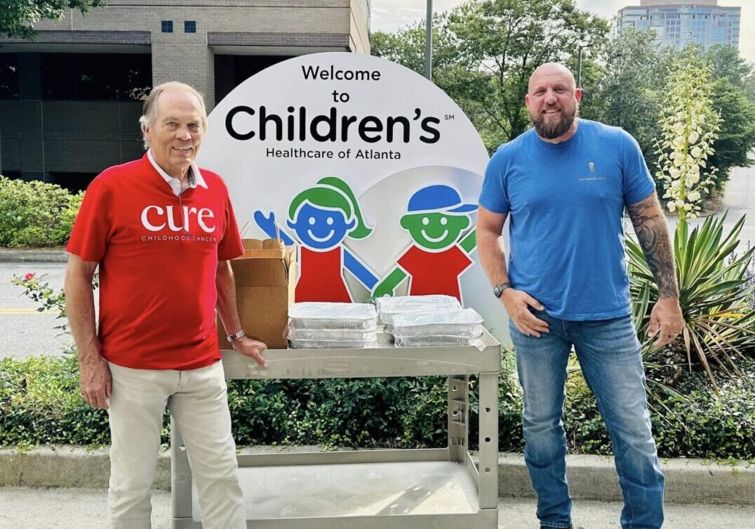 Two men standing next to a sign that says welcome to children 's.