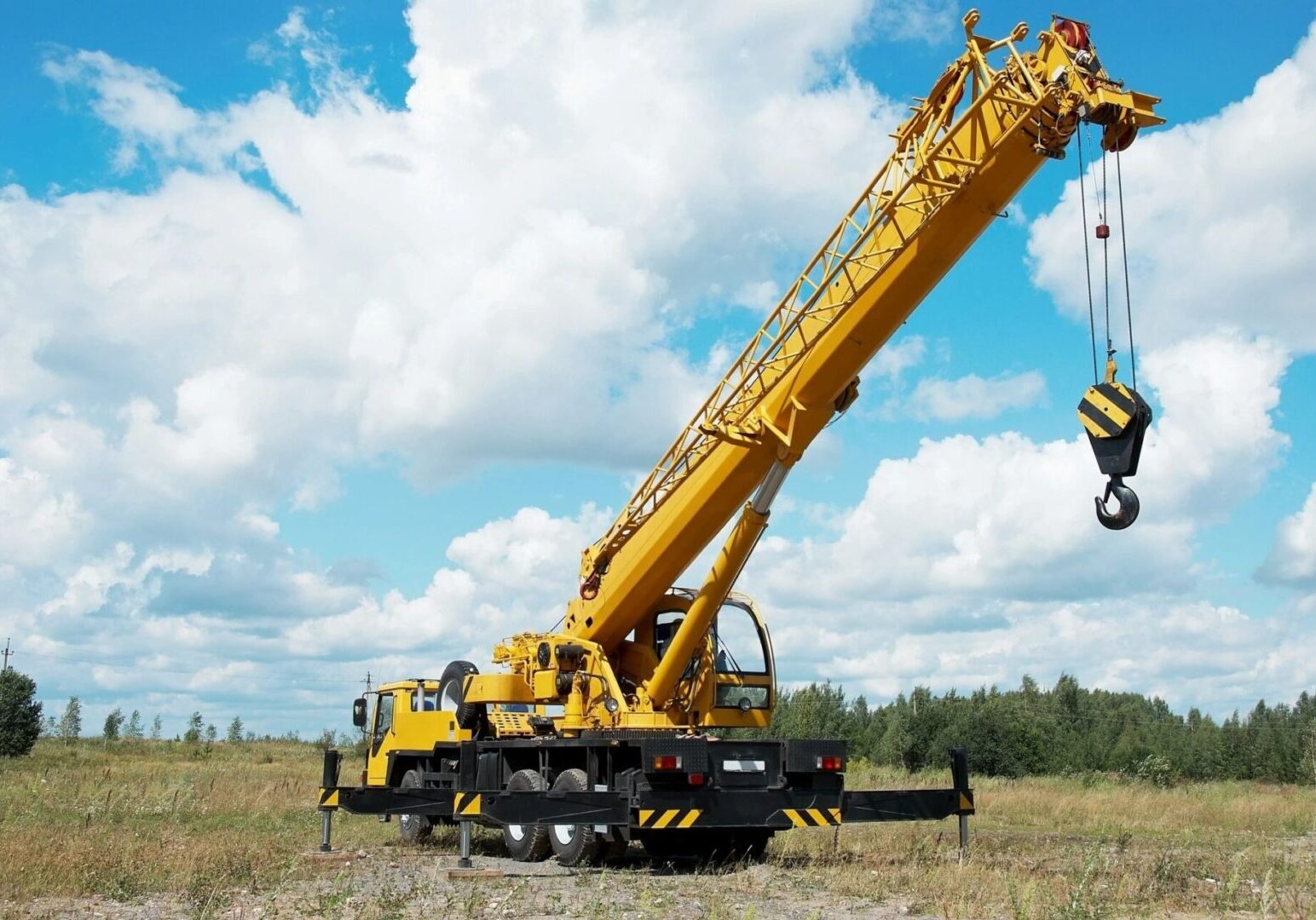 A yellow crane is on the ground in a field.